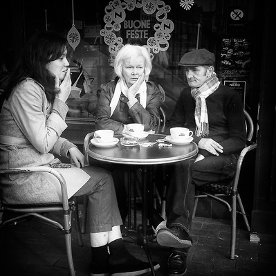 'Two woman and a man sitting down smoking and drinking coffee,Black & White London Street Photography' 