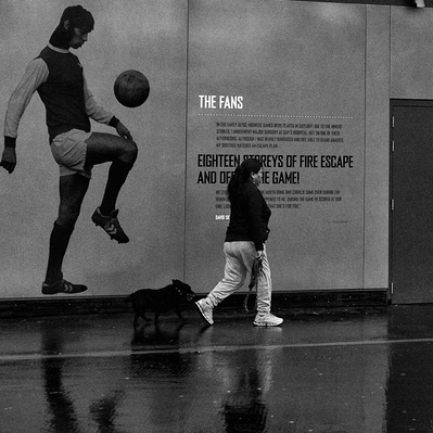 'Woman walks past a football sign walking her dog, Black & White London Street Photography'