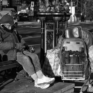 Rough sleeper sitting on a bench, London black-and-white photography