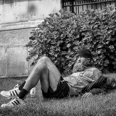 Rough sleeper sunny himself in Trafalgar Square, London black-and-white photography