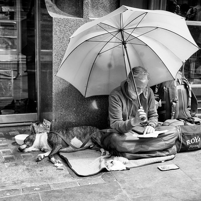 Rough sleeper sitting under his umbrella, London black-and-white for photography