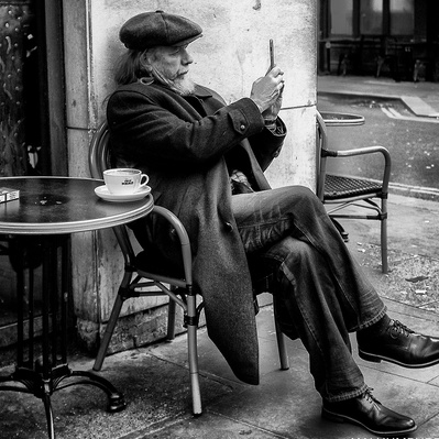 man sitting outside coffee shop, London Street photography black and white
