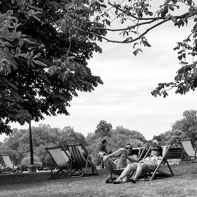 A man sunbathing on a deck chair, Hyde Park London black-and-white photography