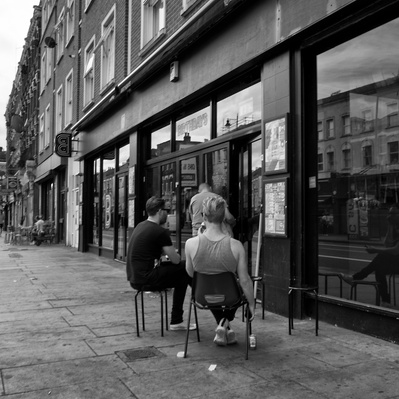 Two people sitting on chair Dalston East London black-and-white photography