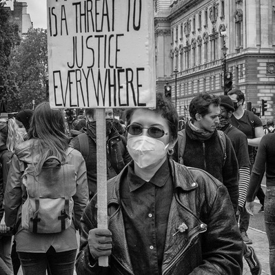 'Woman holding a placard outside houses of parliament at the Black Lives Matter Protests, Black and White London Street Photography'
