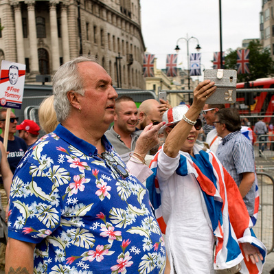 'Tommy Robinson Supporter wearing a bright shirt walking down Whitehall, London Colour Street Photograph'