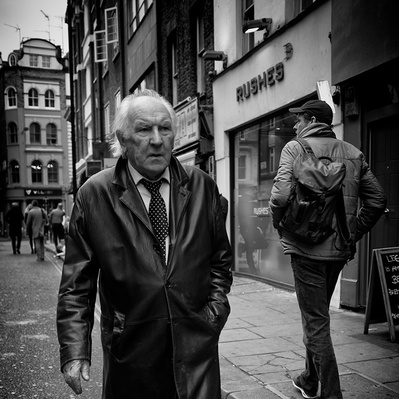 Men in leather coat walking down old Compton Street, Soho, London black-and-white photography