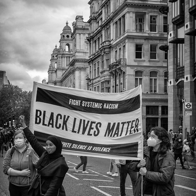 'Women holding a placard outside houses of parliament at the Black Lives Matter Protest, Black and White London Street Photography'
