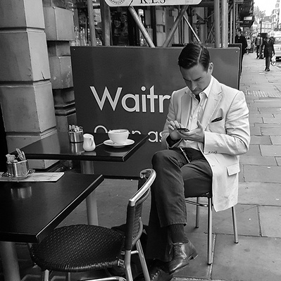 Man sits under a danger sign, Marleybone London, black and white photography