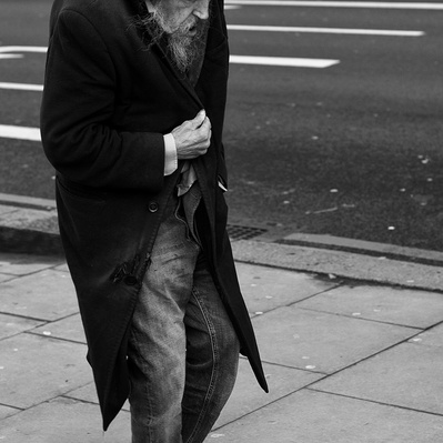 Man walking down the street trying to keep warm central London black-and-white photography