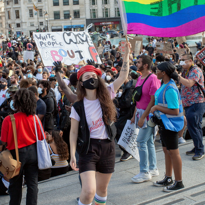 'Young Protester at Black Lives Matter Protests, Standing on the steps in Trafalgar Square waving a flag, London Colour Street Photography'