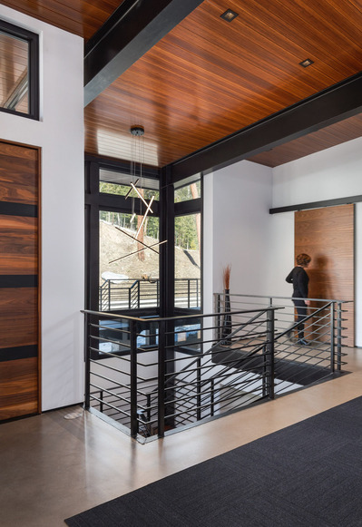 A midcentury modern foyer, with a woman sliding a barn door open to the hallway.
