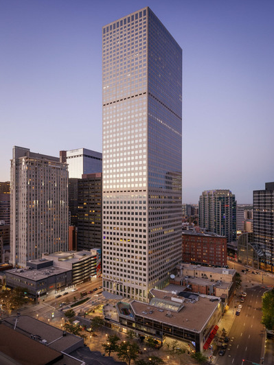 Exterior twilight photograph of Republic Plaza in Denver, showcasing the building illuminated against the evening purple sky.
