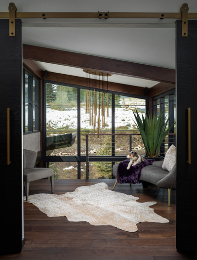 A midcentury modern second floor landing  with a puppy laying in the chair, looking out the window.