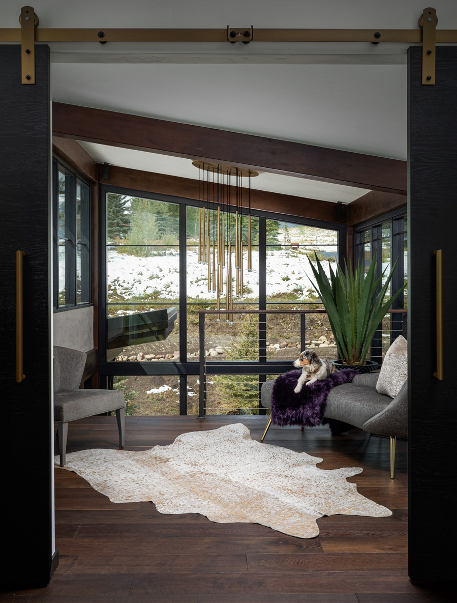 A midcentury modern second floor landing  with a puppy laying in the chair, looking out the window.