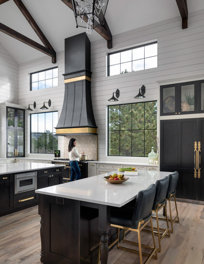 A large custom farmhouse villa kitchen, with a women at the stove looking out the window.