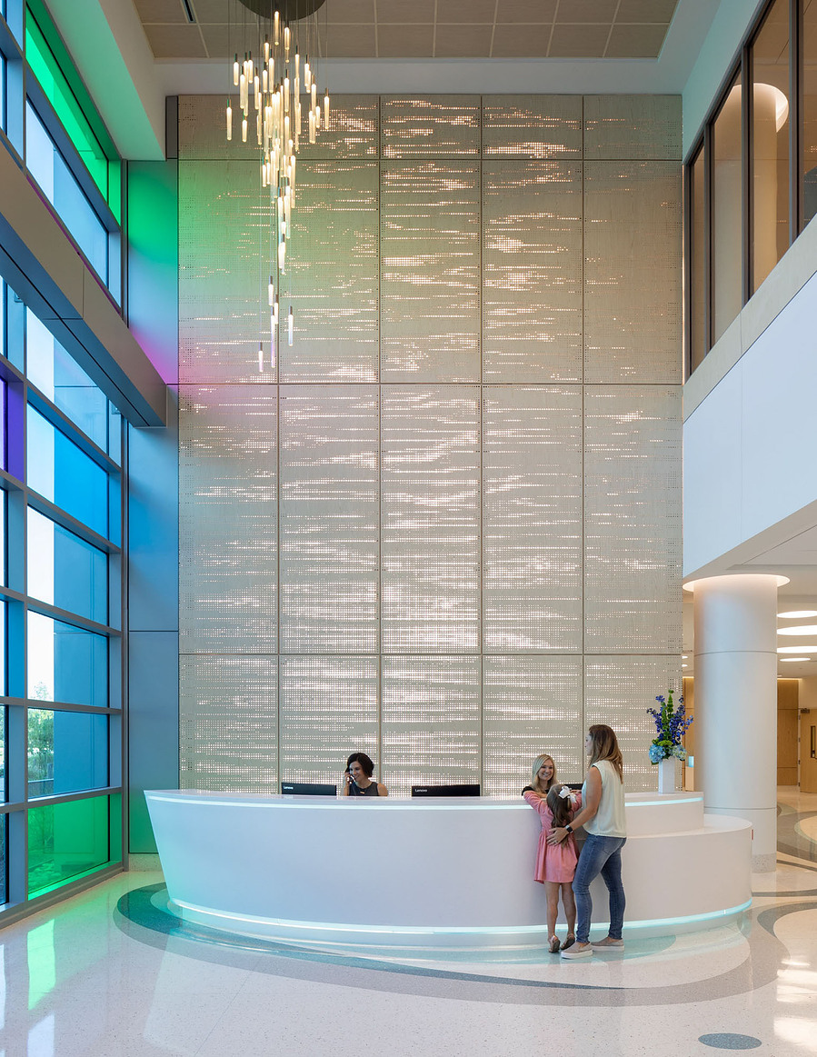 A grand lobby in a modern children’s hospital designed by HKS Architects, showcasing a spacious, light-filled atrium with playful design elements, colorful accents, and a welcoming atmosphere for patients and families.