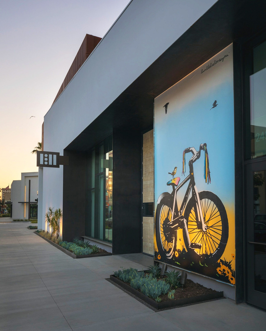 Modern office entrance at dusk with a mural of bicycle.