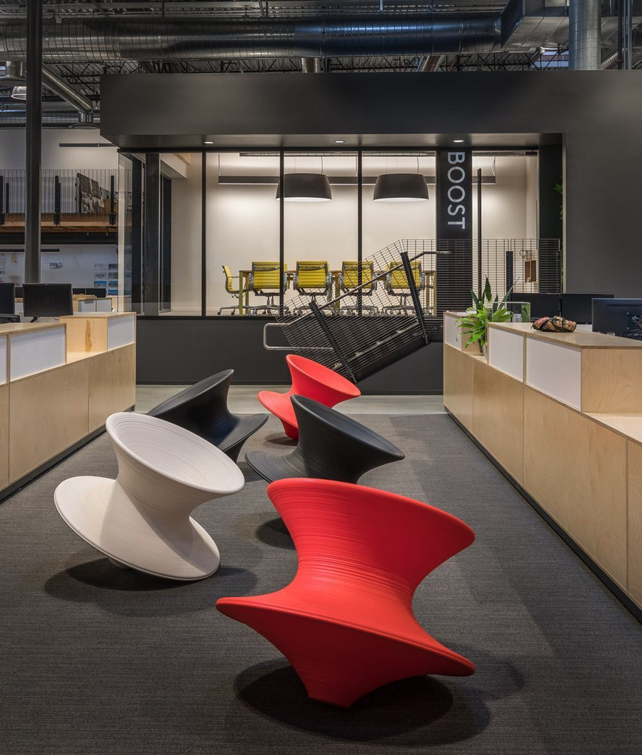 Modern office with magis spun chairs and a private meeting space with yellow chairs in the background.