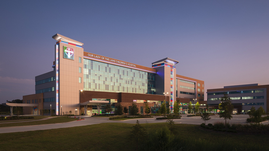 A modern hospital building with reflective glass of the purple and orange dusk sky.