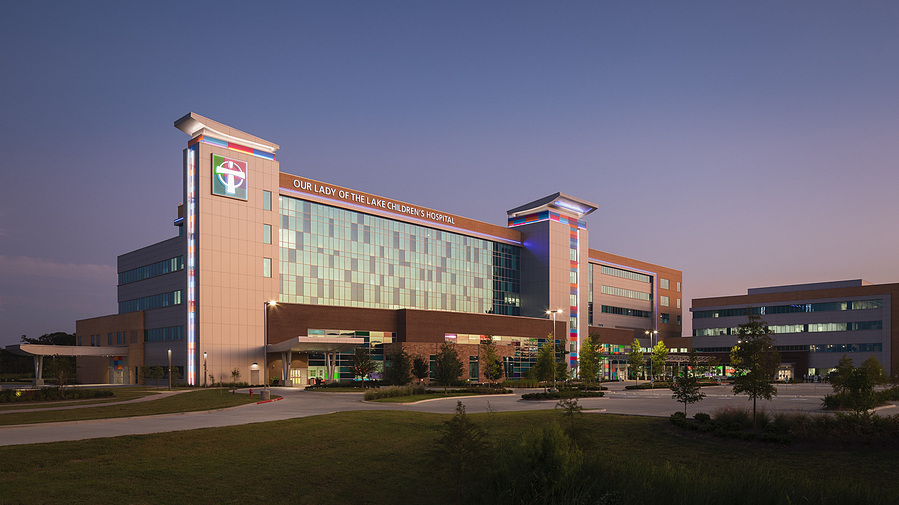 A modern hospital building with reflective glass of the purple and orange dusk sky.