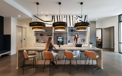 A modern kitchen with two women working and talking in a multifamily building lobby.