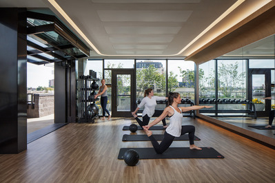 3 women in a modern designed yoga studio with clean lines and garage door open to a terrace.