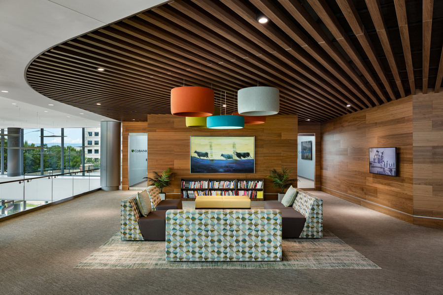 Office seating area with modern vibrant furniture and large wooden ceiling and walls.