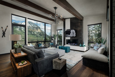 A large modern great room of a midcentury modern home with a massive windows and mountain views.