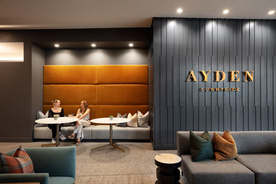 Lobby at The Ayden multifamily building in Denver, designed by OZ Architecture, emphasizing modern decor and ambiance with two ladies enjoying conversation.