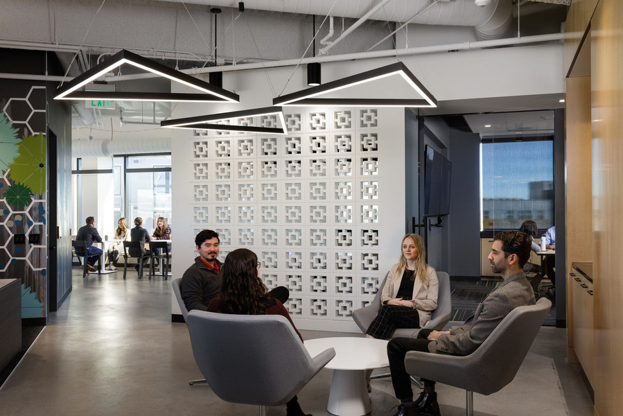 A modern office break room with lots of people sitting and socializing.