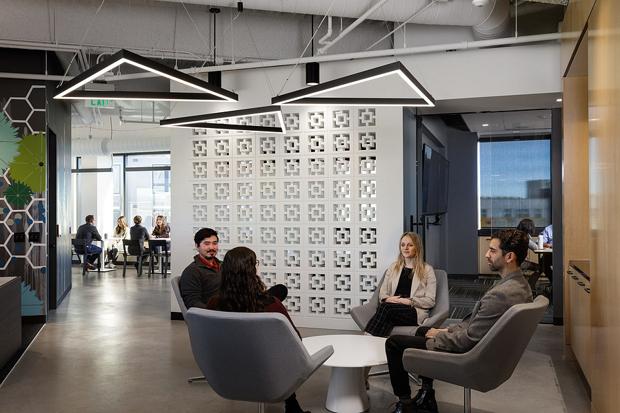A modern office break room with lots of people sitting and socializing.