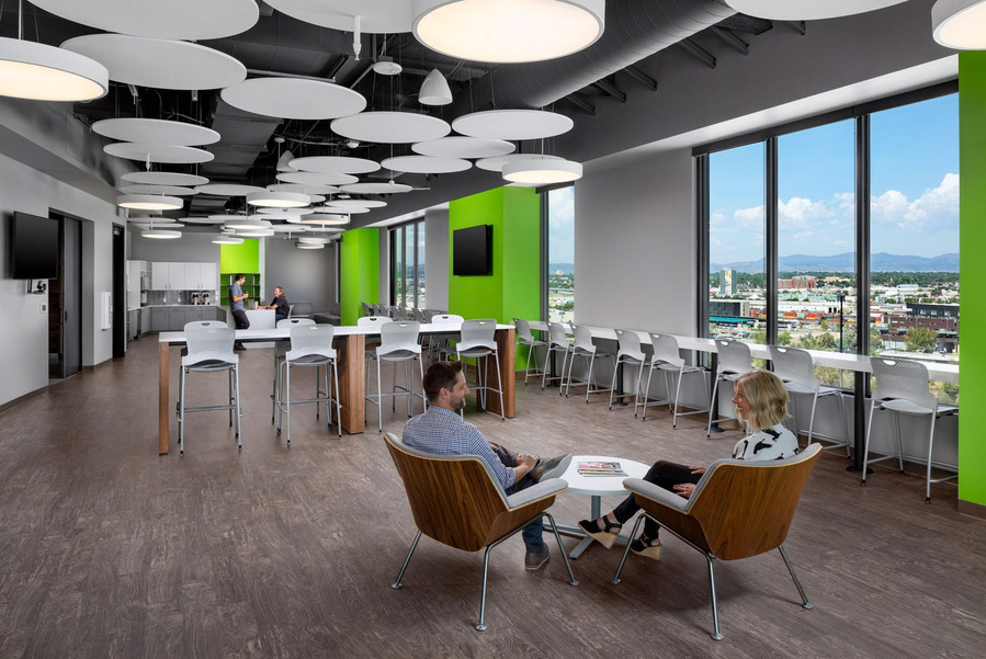 A modern large office break room with green walls and huge mountain views.