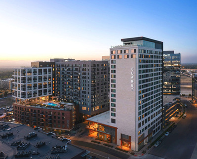 Aerial twilight view of Kimpton Claret Hotel in Denver, showcasing the hotel's exterior illuminated under the evening sky and rooftop bar night life.