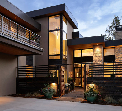 A midcentury modern home with the gate open to a courtyard at twilight.