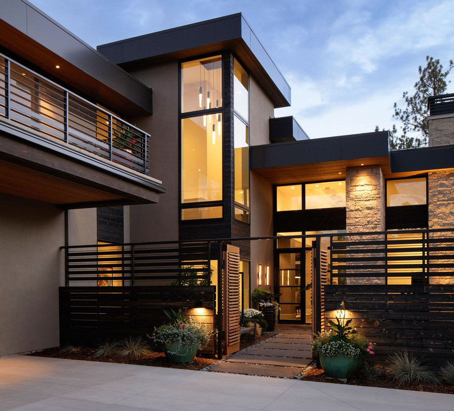 A midcentury modern home with the gate open to a courtyard at twilight.