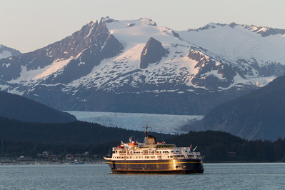 Scenic photograph of the marine vessel Taku on the Alaska Marine Highway, with Mendenhall Glacier visible in the background.