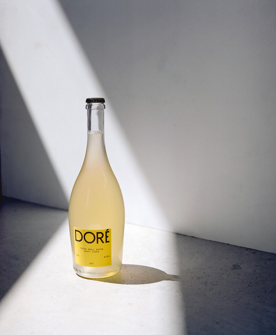 Product photo for Doré Cider, featuring bottles in a minimalist setting under vibrant sunlight. A crisp, natural aesthetic reflecting the essence of premium cider.