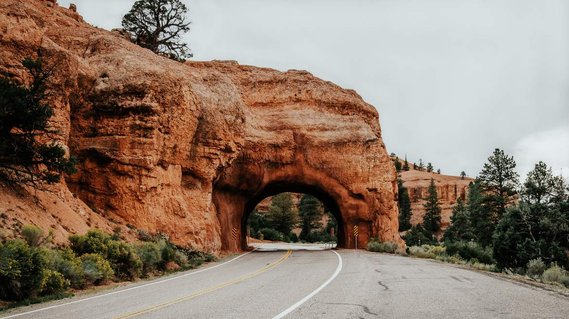 Tunnel shaped rock formation over a road.