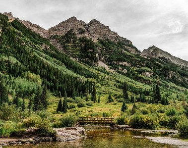 Landscape photography: footbridge crossing over a creek in front of a mountain