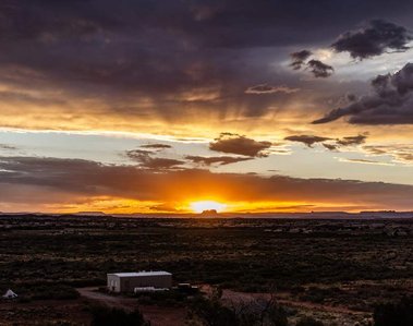 The sun bursts through a desert canyon silhouette coloring the Utah sky