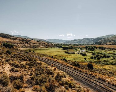 Railroad track leading to a pasture lined by mountains in Colorado