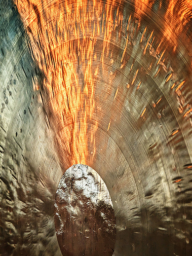 Close up of a wind gong. Light reflects upon its surface.