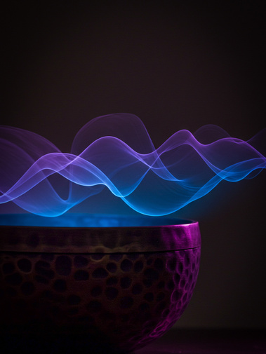 Purple and blue sound waves radiate from a therapeutic singing bowl.