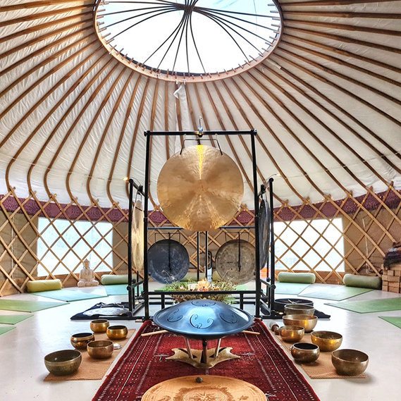 Earth Resonance sound bath setup at a yurt in the Yoga Garden at Knepp Wildlife Safaris, East Sussex. Gongs, singing bowls and handpan.