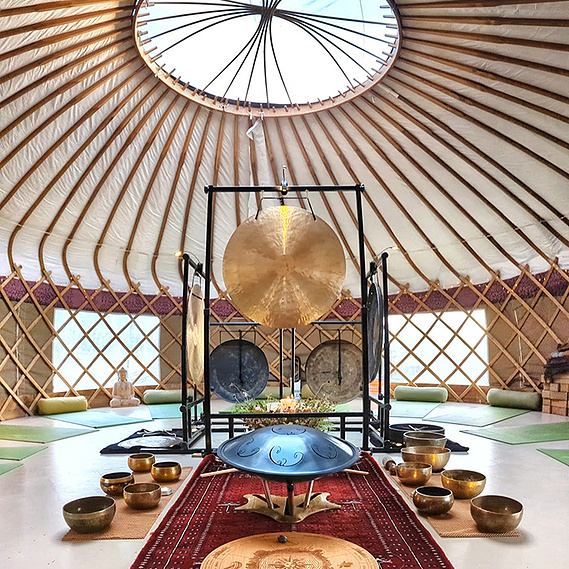 Earth Resonance sound bath setup at a yurt in the Yoga Garden at Knepp Wildlife Safaris, East Sussex. Gongs, singing bowls and handpan.