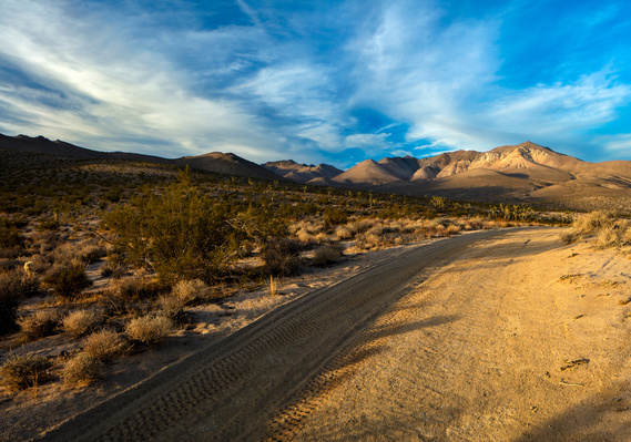 Desert road, with blue sky and clouds, traveling through California's High Mojave Desert.