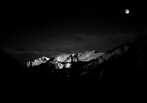 The winter moon lights the snow covered  mountians of the Wasatch Range, Utah.