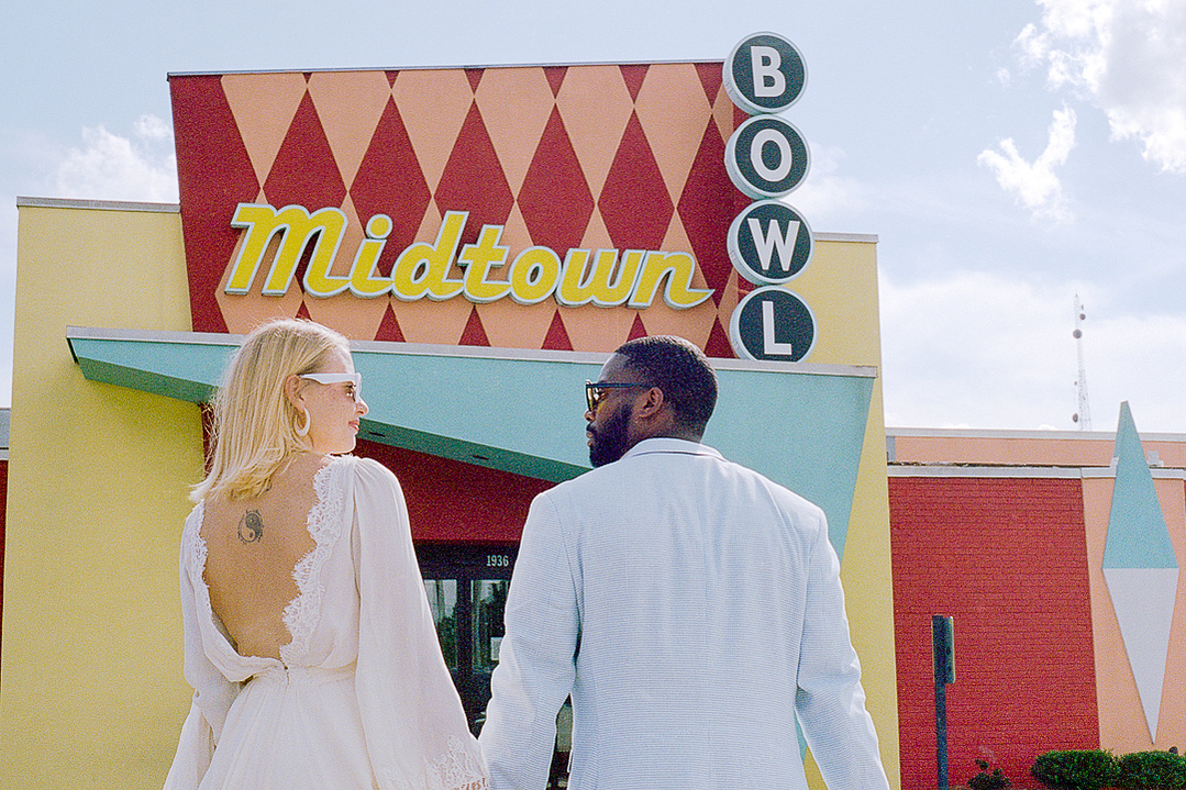 Photograph of the back of a bride and groom outside the iconic retro Midtown Bowl bowling alley in Atlanta Georgia
