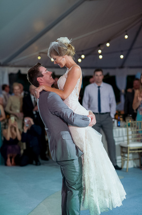 a colorful wedding photograph of a bride and groom during their first dance. this photo features the groom lifting the bride